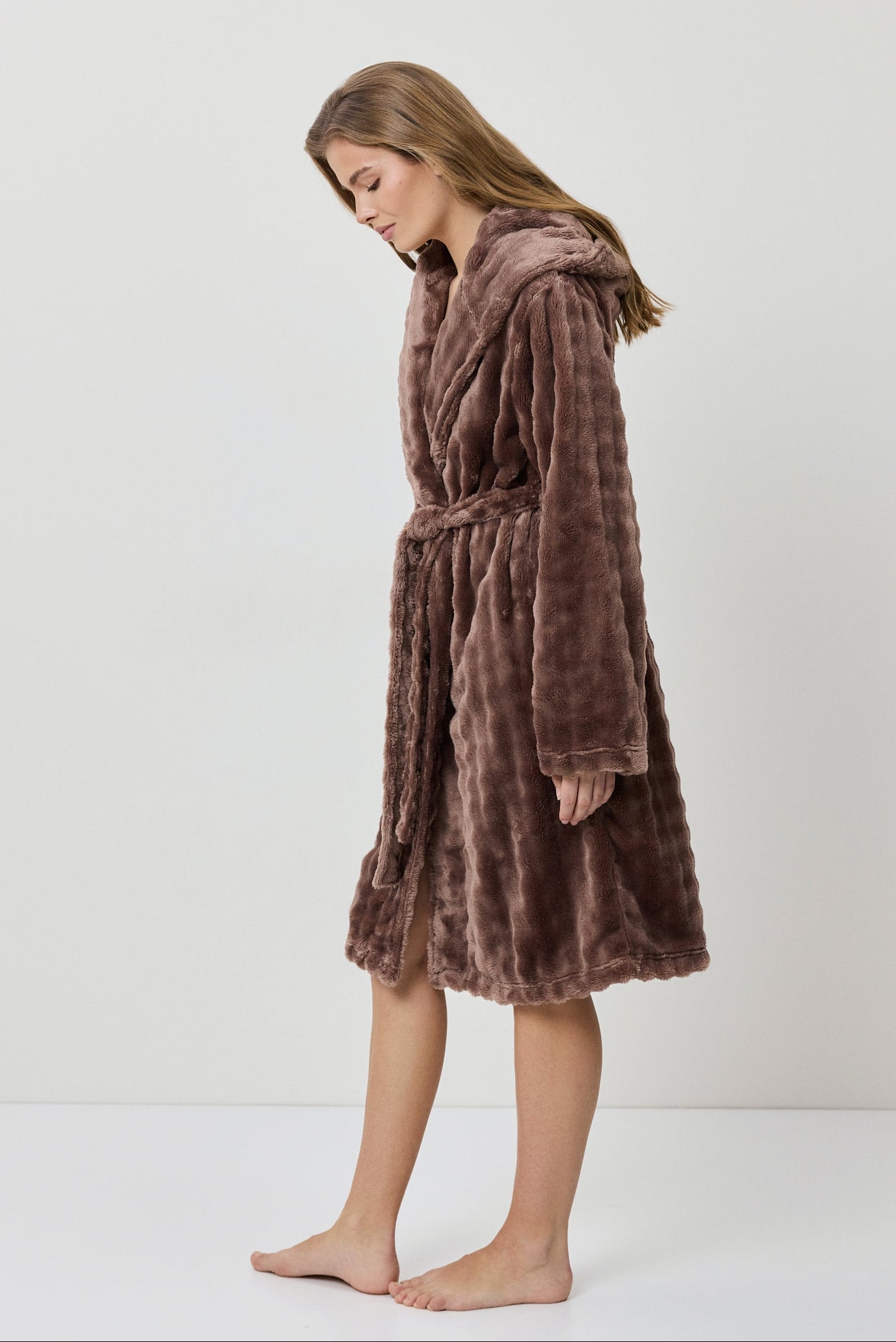 Woman wearing a brown plush robe on a white background