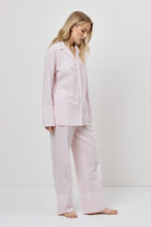 Woman wearing a pink checkered pajama set against a white background