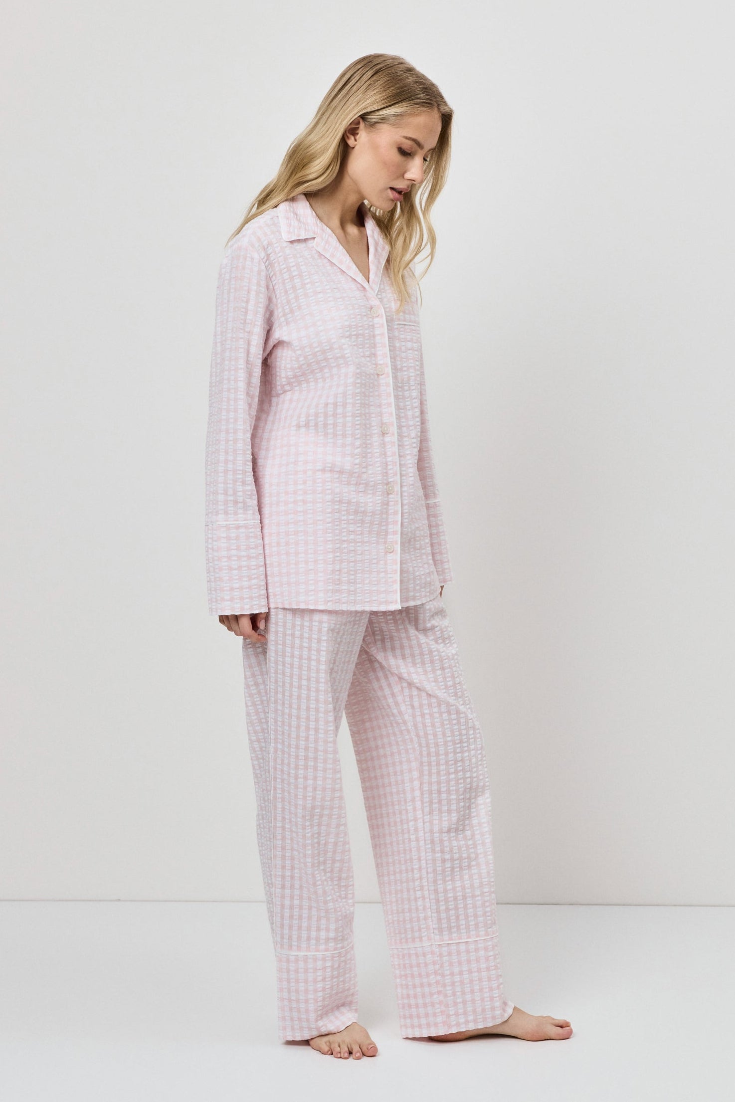 Woman wearing a pink checkered pajama set against a white background