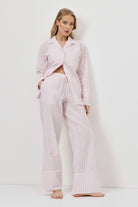 Woman wearing a pink checkered pajama set against a white background