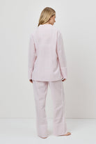 Woman wearing a pink checkered pajama set against a white background
