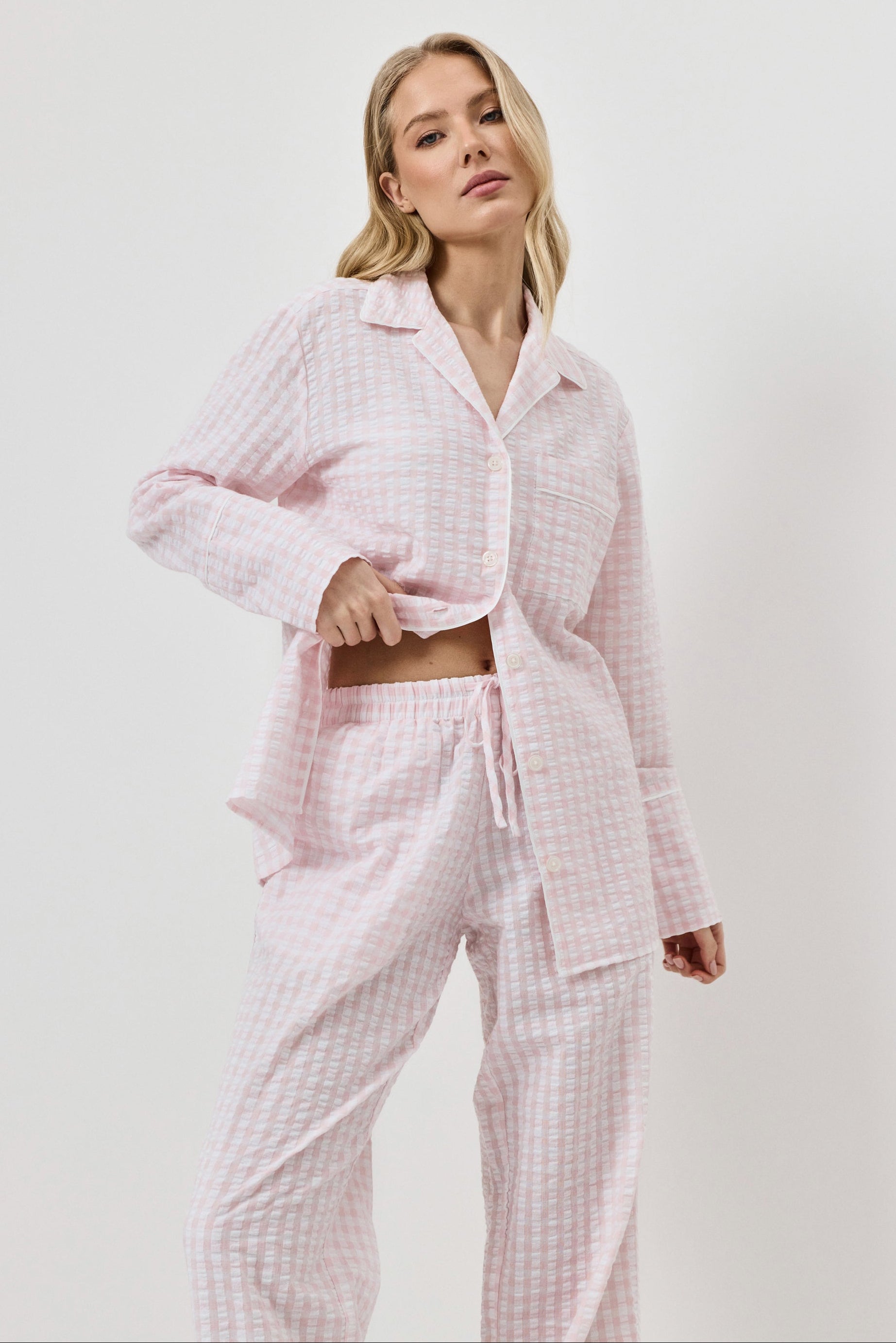 Woman wearing a pink checkered pajama set on a white background
