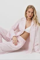 Woman wearing a pink checkered pajama set on a white background