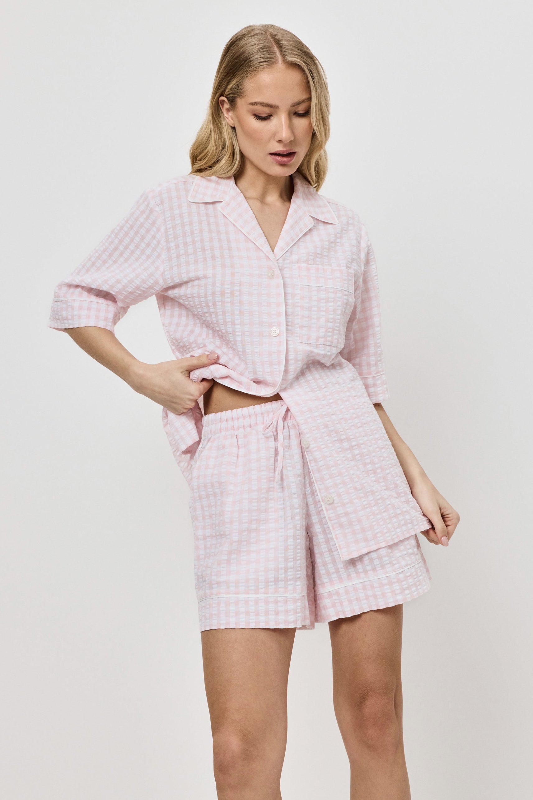 Woman wearing a pink checkered pajama set on a white background