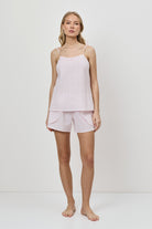 Woman wearing a pink checkered pajama set against a white background