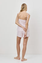 Woman wearing a pink checkered pajama set against a white background