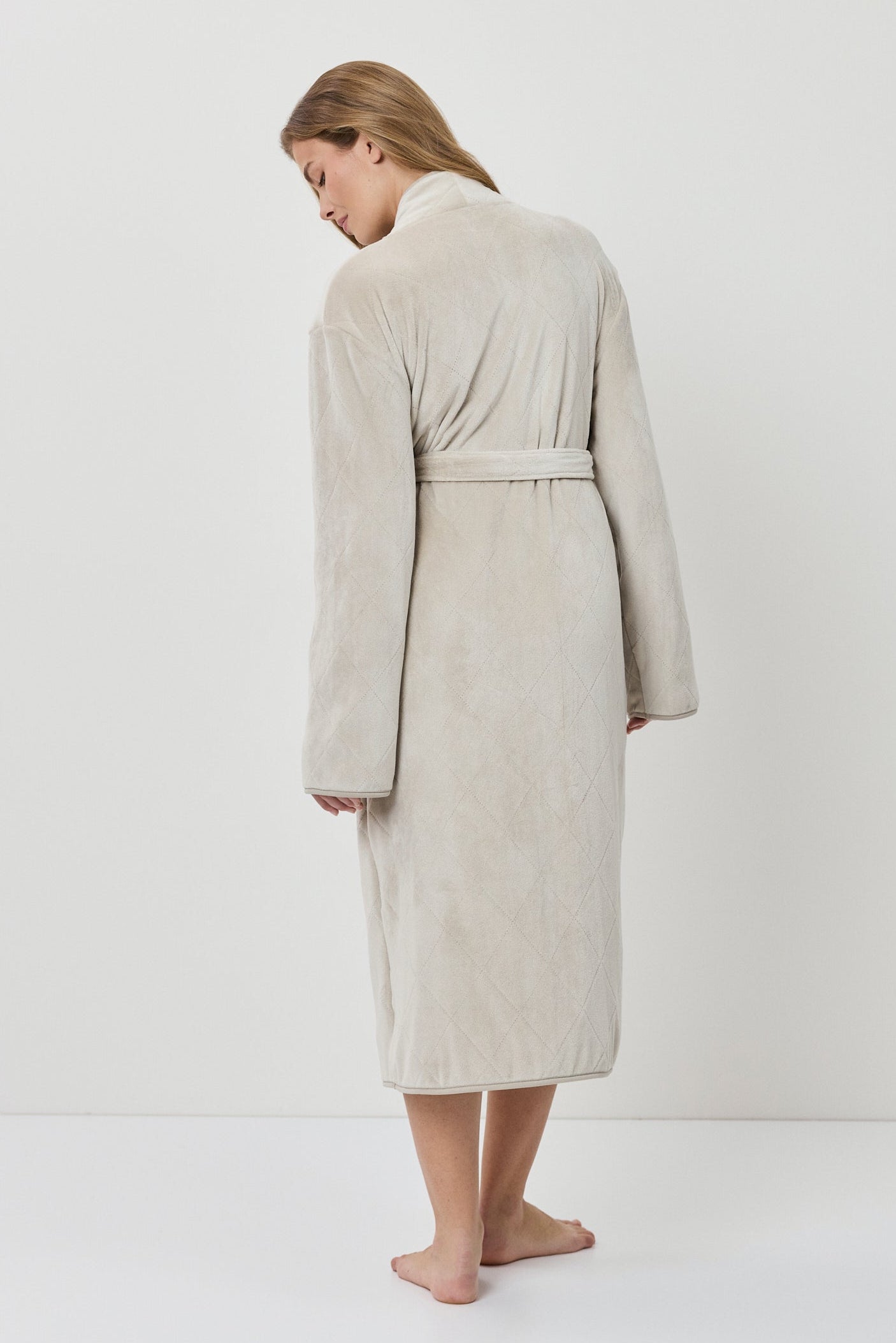 Woman wearing a beige robe against a white background