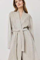 Woman wearing a beige robe against a white background