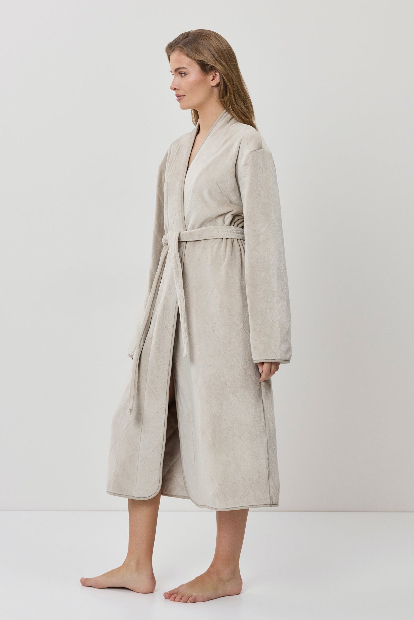 Woman wearing a beige robe against a white background