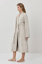 Woman wearing a beige robe against a white background