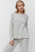 Woman wearing a black and white striped long-sleeve top and pants on a white background