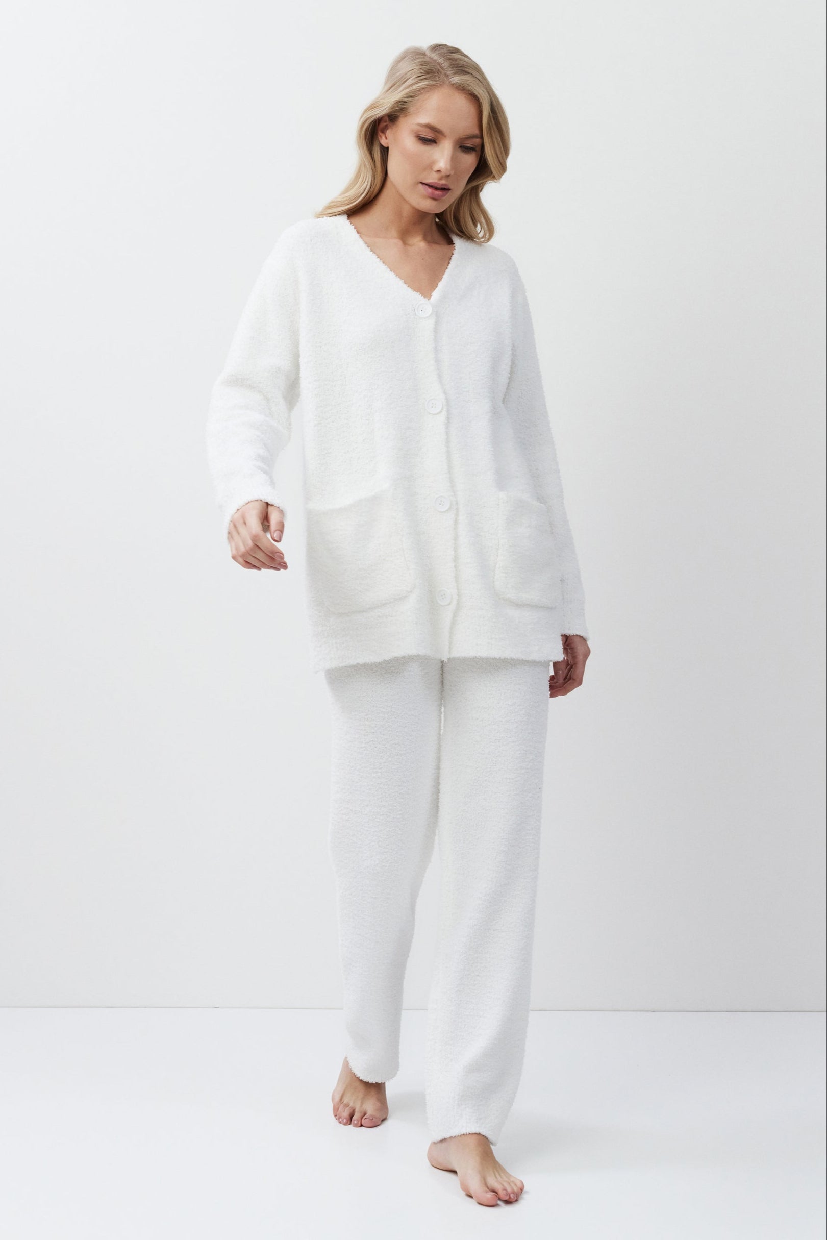 Woman wearing a white loungewear set on a plain background