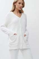 Woman wearing a white cardigan on a plain background