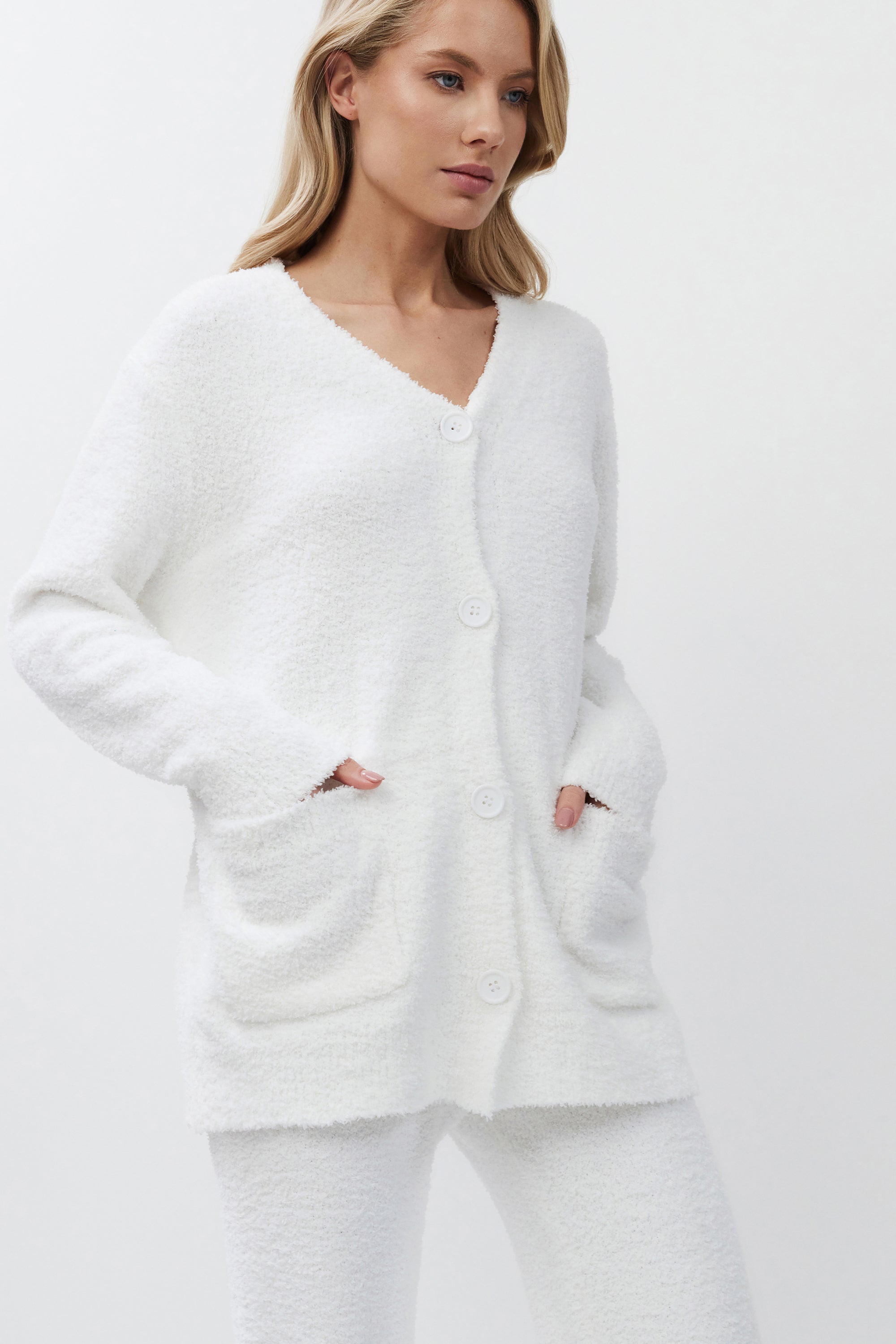 Woman wearing a white cardigan on a plain background