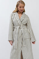 Woman wearing a long, striped batrobe against a plain background