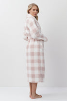 Woman wearing a pink and white checkered bathrobe on a white background