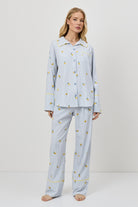 Woman wearing light blue pajamas with a lemon embroideries on a white background