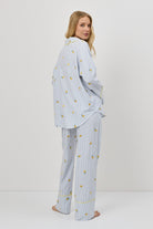 Woman wearing a light blue pajama set with a lemon emroyderies on a white background