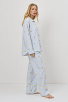 Woman wearing light blue pajamas with a lemon embroideries on a white background