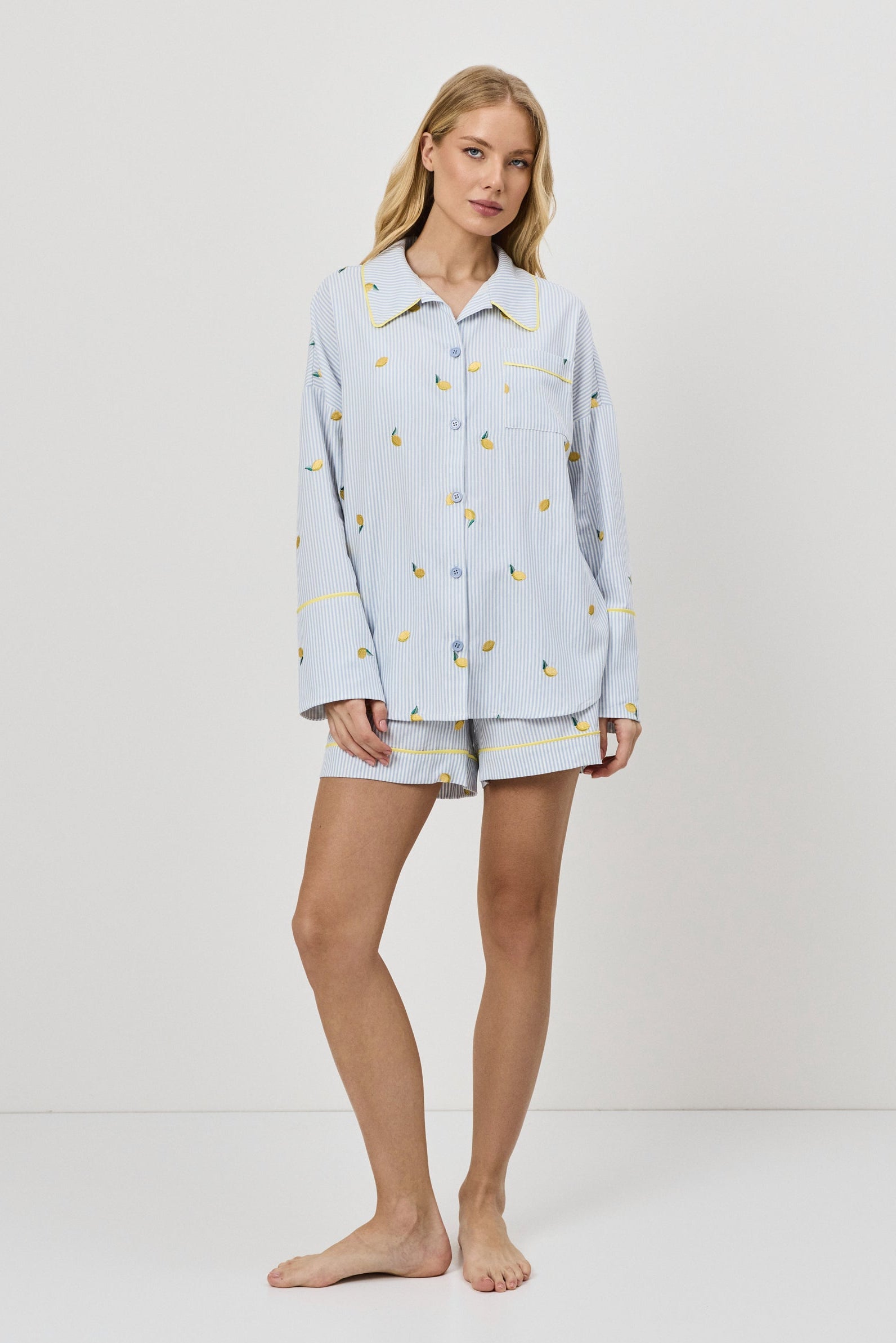 Woman wearing a light blue pajama set with a lemon embroideries on a white background