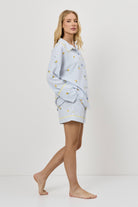 Woman wearing a light blue pajama set with lemon embroideeries on a white background