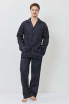 Man wearing a navy polka dot pajama set on a white background