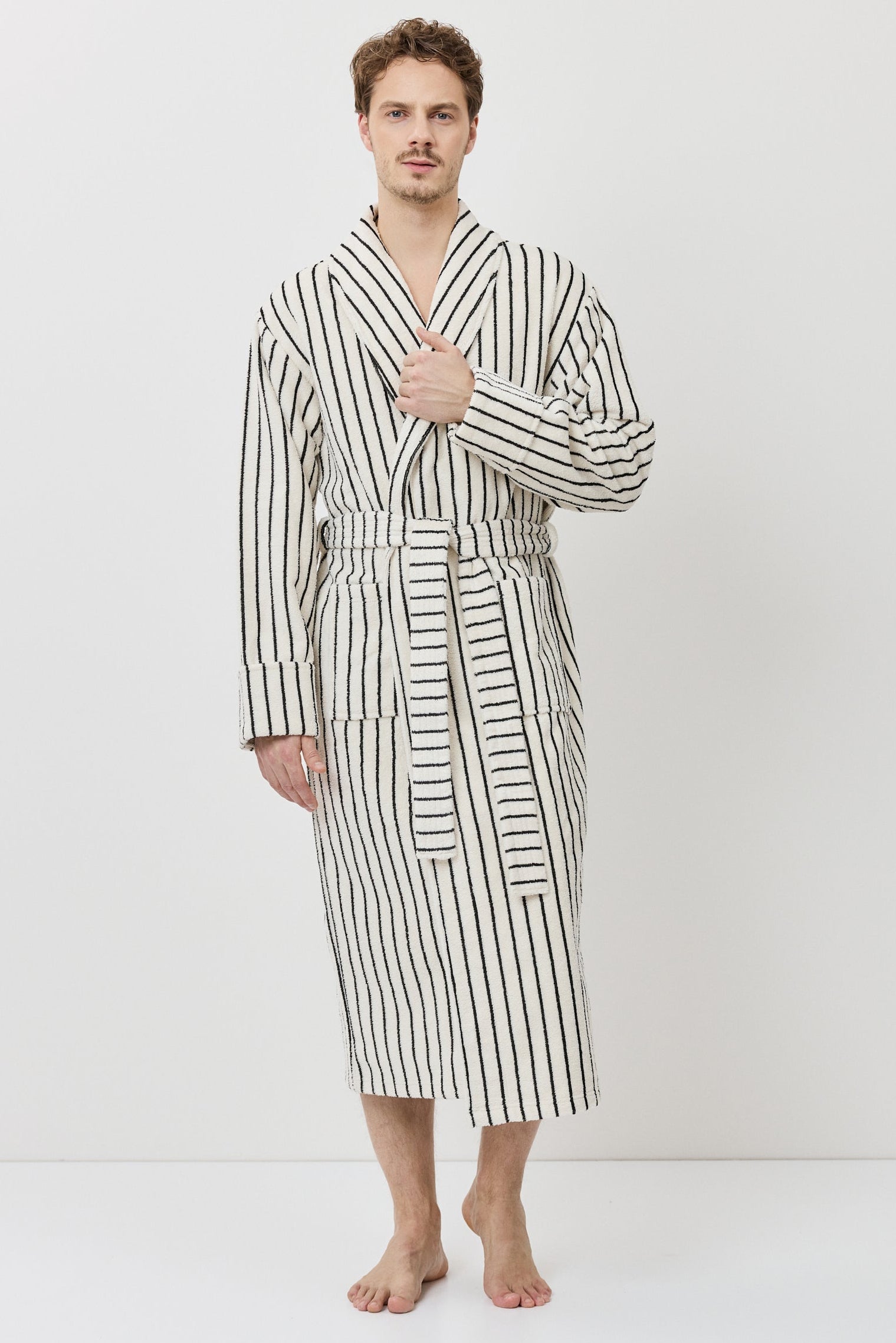 A man wearing a long-sleeved striped bathrobe with black and white vertical stripes.