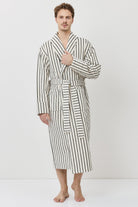 A man wearing a long-sleeved striped bathrobe with black and white vertical stripes.