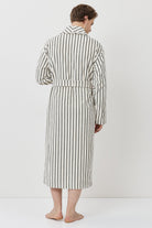 A man wearing a long-sleeved striped bathrobe with black and white vertical stripes.
