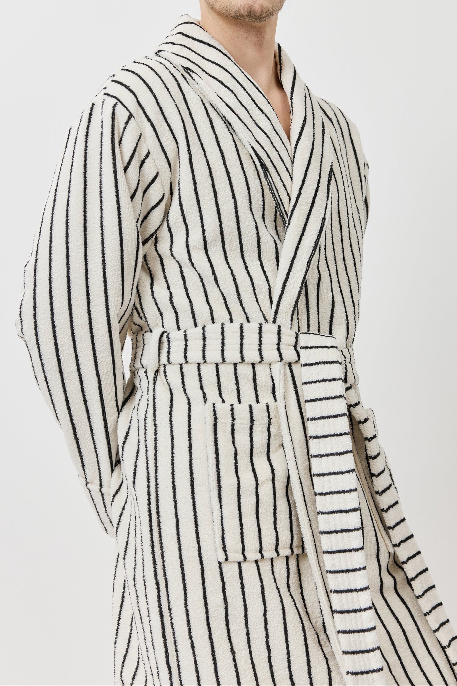 A man wearing a long-sleeved striped bathrobe with black and white vertical stripes.