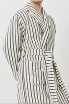 A man wearing a long-sleeved striped bathrobe with black and white vertical stripes.