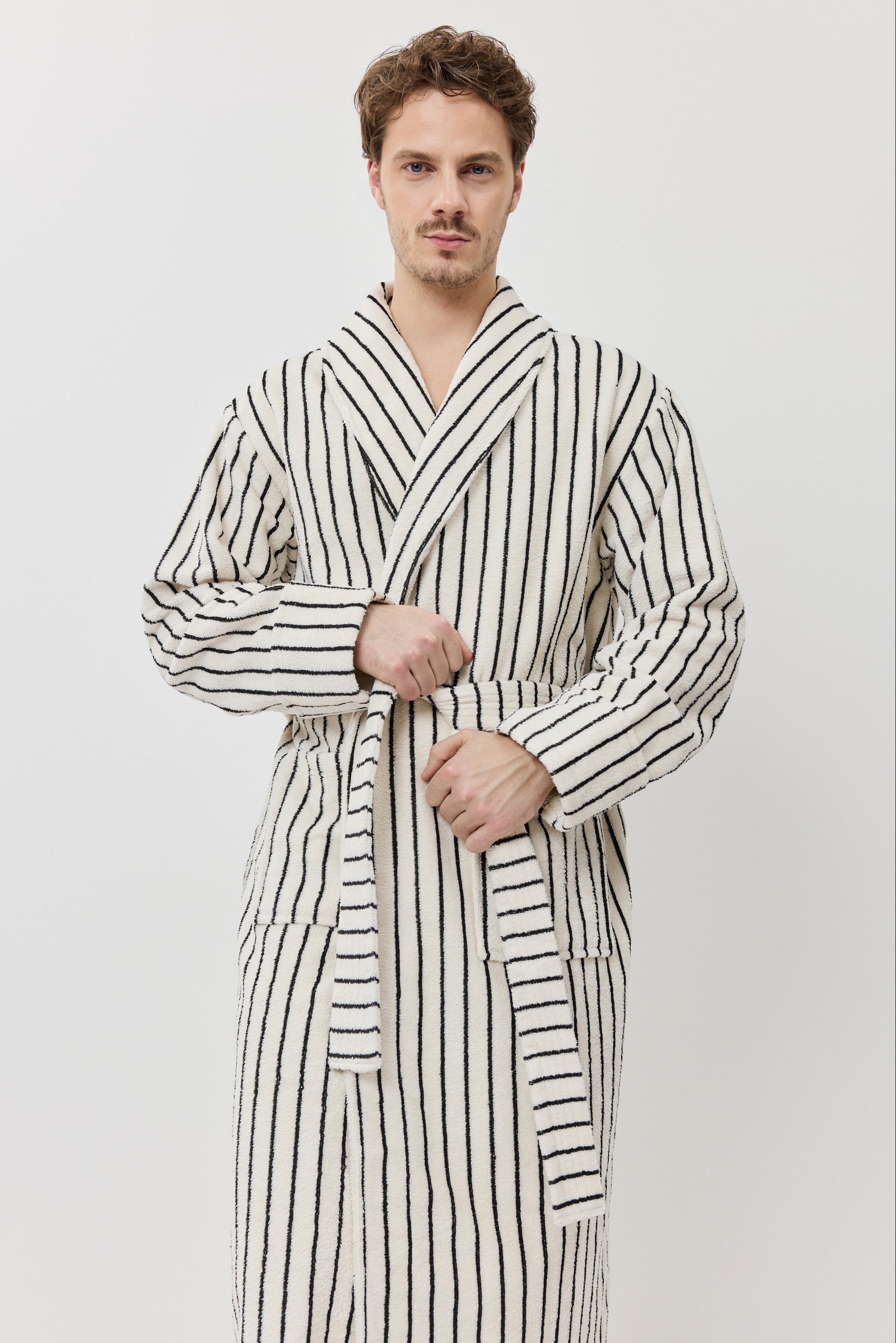 A man wearing a long-sleeved striped bathrobe with black and white vertical stripes.