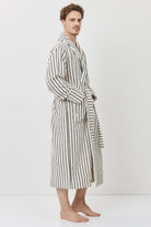A man wearing a long-sleeved striped bathrobe with black and white vertical stripes.