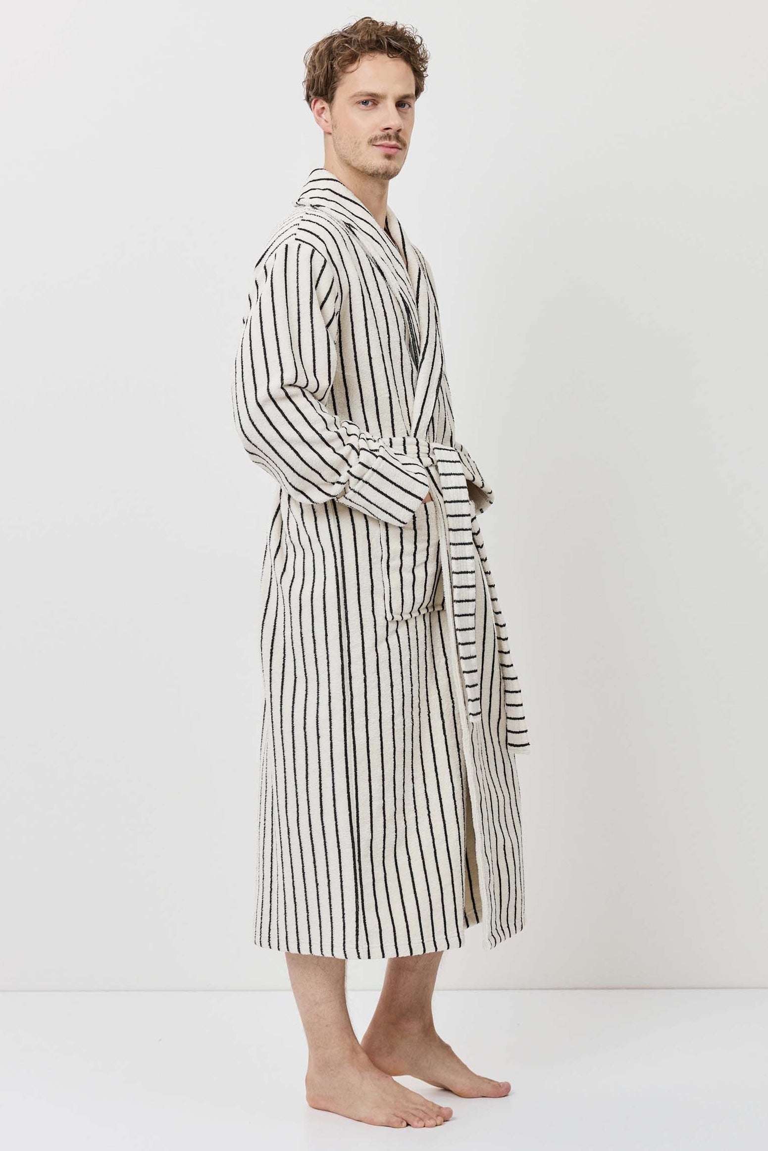 A man wearing a long-sleeved striped bathrobe with black and white vertical stripes.
