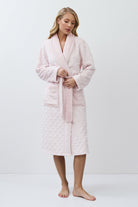 Woman wearing a pink bathrobe against a white background