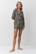 Woman wearing a patterned pajama set with shorts on a white background