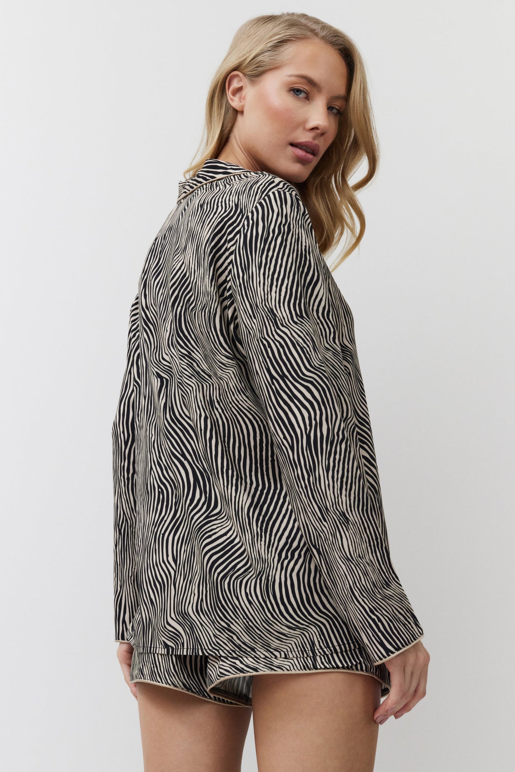 Woman wearing a patterned shirt and shorts on a white background