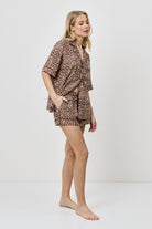 Woman wearing a leopard print pajama set on a white background