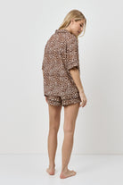 Woman wearing a leopard print pajama set on a white background