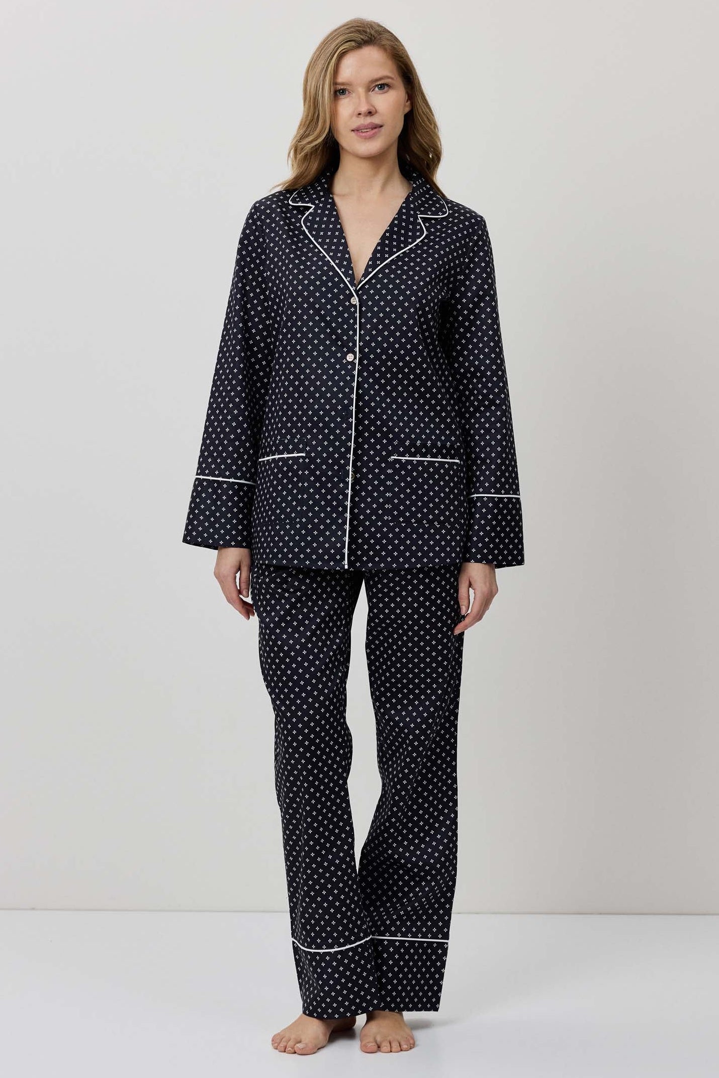 Woman wearing a black polka dot pajama set on a white background