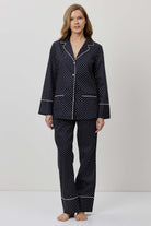 Woman wearing a black polka dot pajama set on a white background