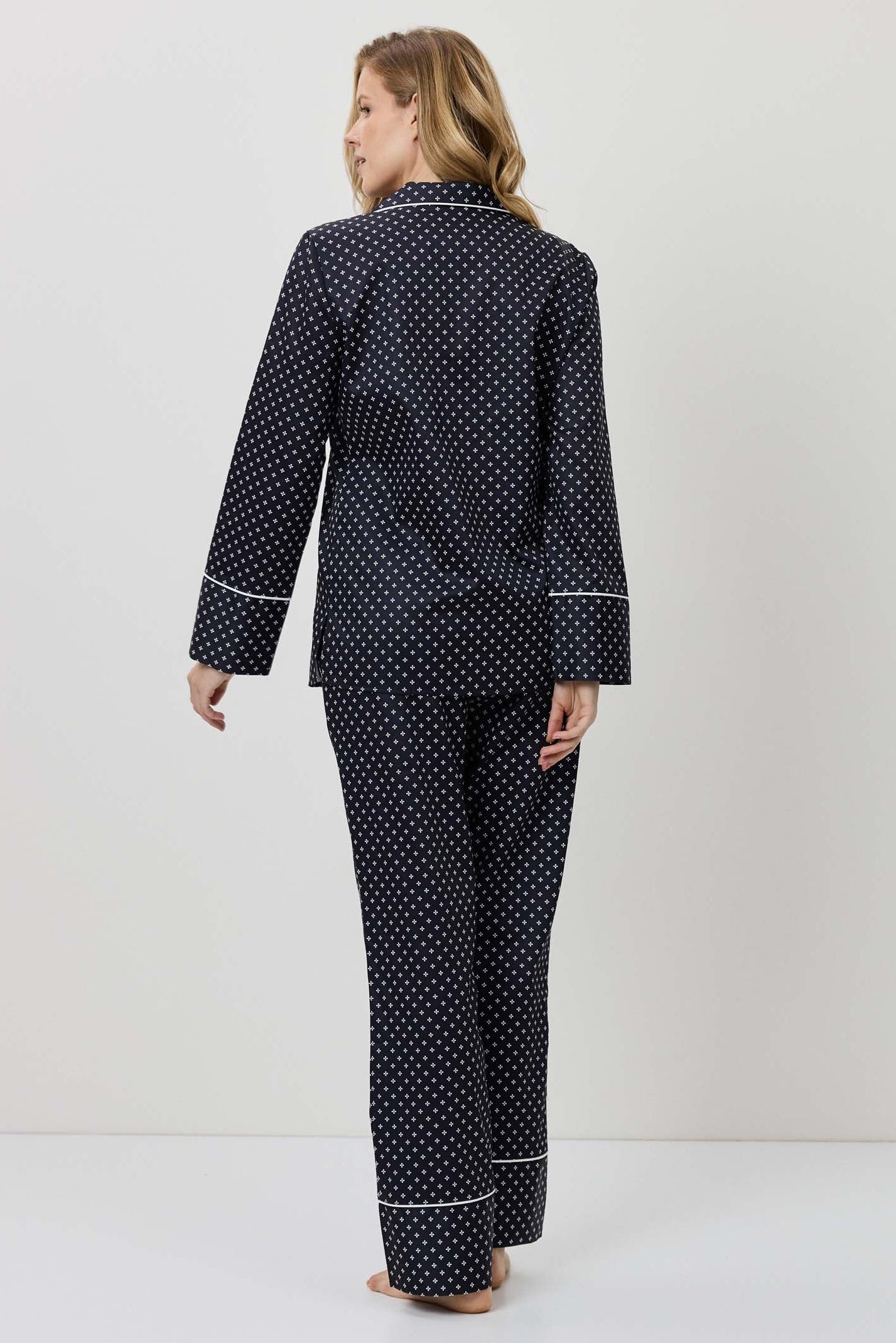 Woman wearing a navy polka dot pajama set against a white background