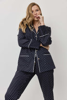 Woman wearing a navy polka dot pajama set on a light gray background