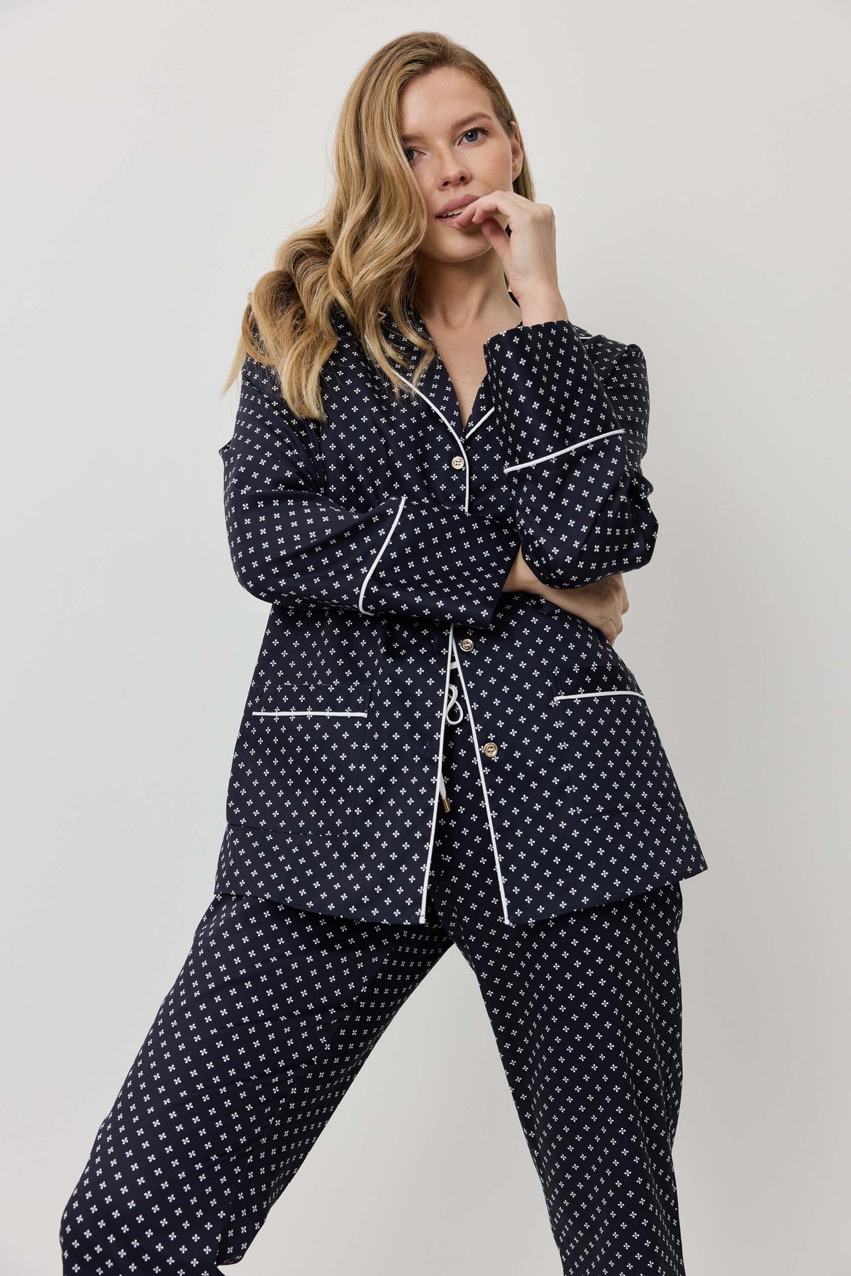 Woman wearing a navy polka dot pajama set on a light gray background