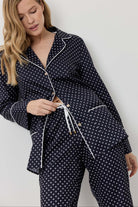 Woman wearing a navy blue polka dot pajama set against a white background