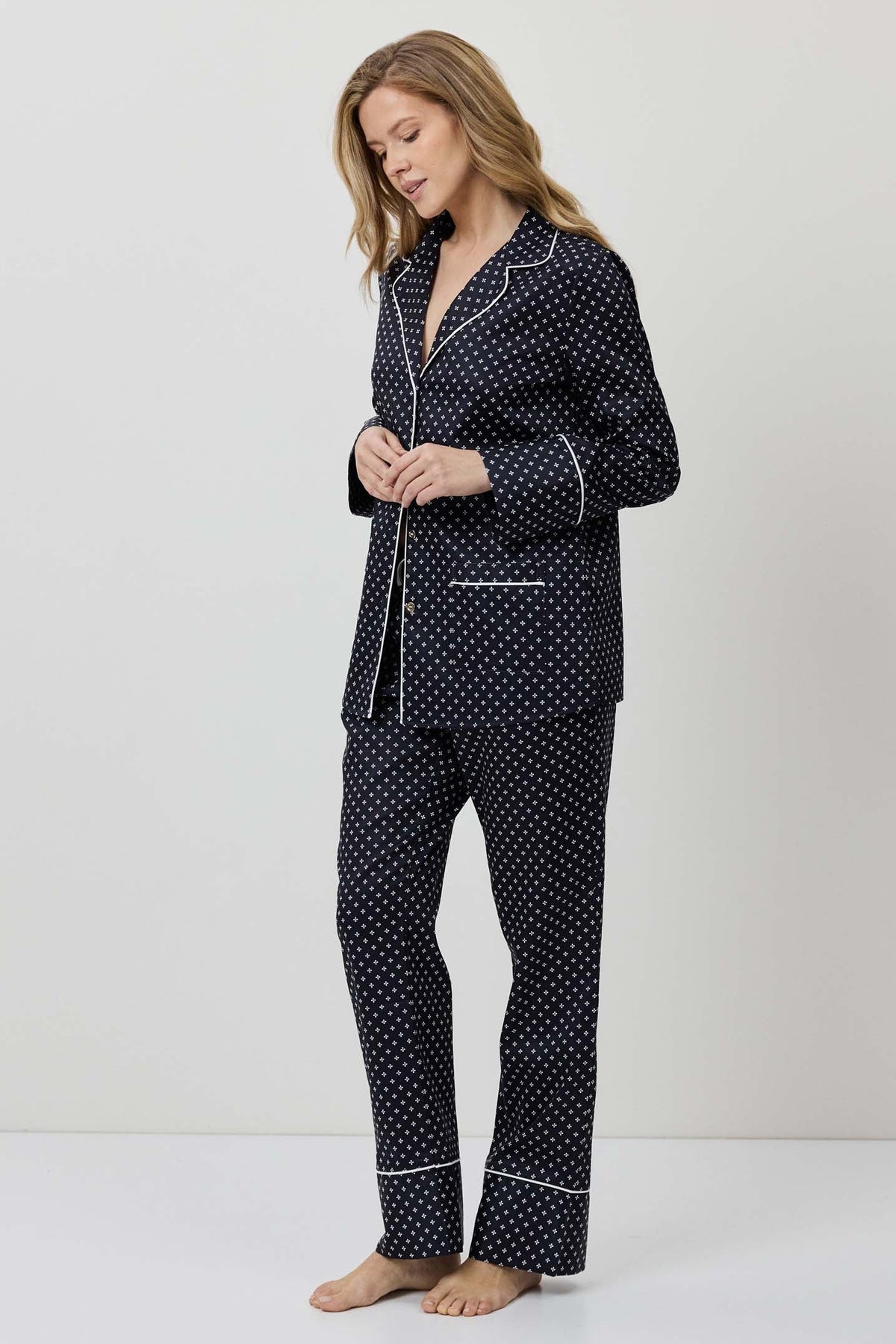 Woman wearing a navy polka dot pajama set on a white background