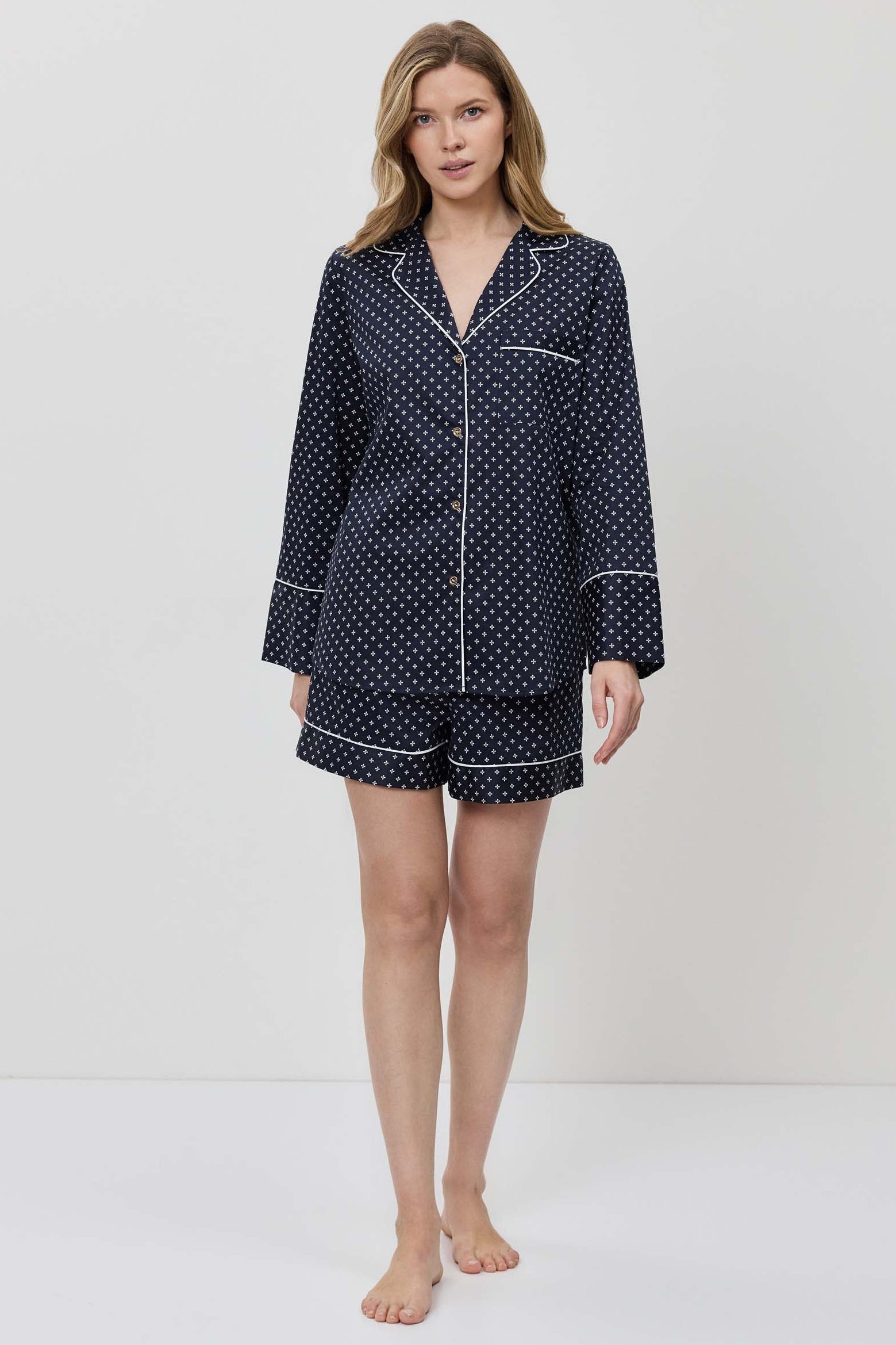 Woman wearing a navy blue polka dot pajama set on a white background