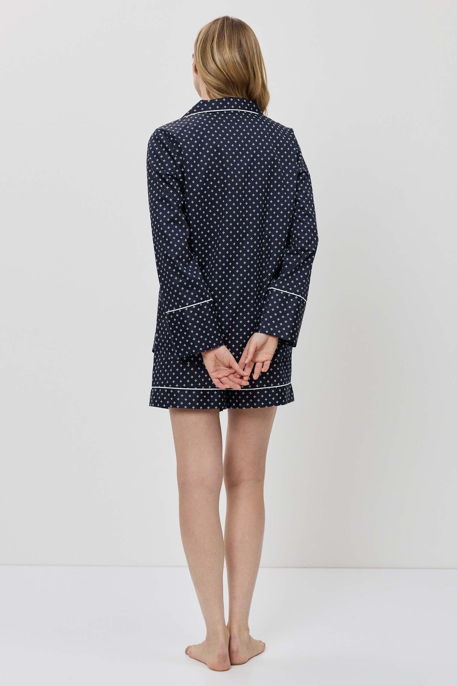 Person wearing a navy blue polka dot robe on a white background