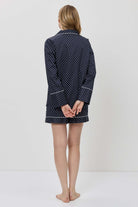 Person wearing a navy blue polka dot robe on a white background