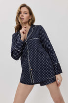 Woman wearing a navy blue polka dot pajama set on a white background